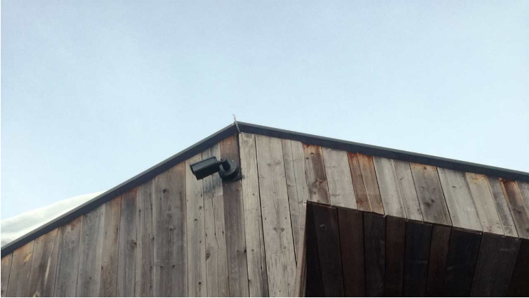 Schwarz lackierte HIKVISION QHD 1400p Livestreaming Webcam an einer Holzfassade.